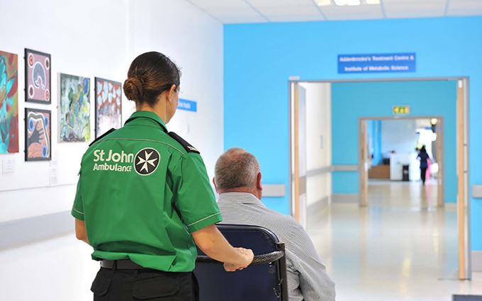 Ambulance_staff_pushing_patient_in_wheelchair_large-pod