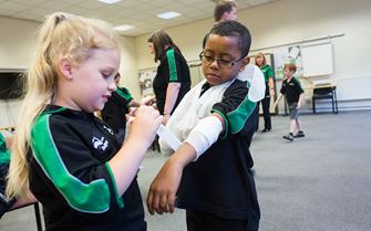 St John Ambulance young people (Badgers) practising putting on arm slings and bandages.