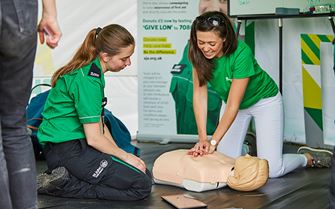 St John Ambulance volunteer teaching a young woman CPR