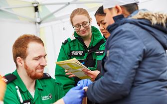 Volunteers treating patient's hand.